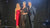 Photo showing Maxine Laceby, a smiling middle aged white woman with short grey hair, standing in between a smiling white man and smiling white woman on a stage. She is holding an award and wearing a glamorous black outfit.