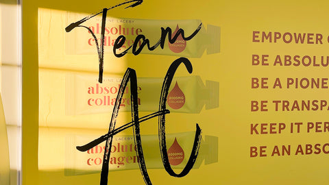 Photo showing a yellow wall with the words TEAM AC written in black alongside some empowering slogans