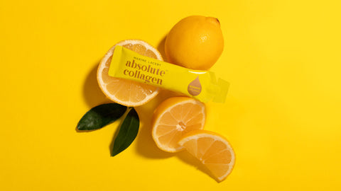 Photo showing a sachet of Absolute Collagen on a bright yellow background with some lemons and halved lemons