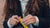 Photo showing a close up of a woman with long brunette hair, she is holding a yellow Absolute Collagen sachet in her hands