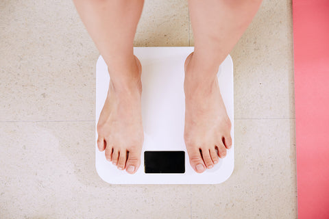 Photo of a white woman's feet on some bathroom scales as she weighs herself