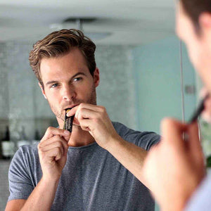 Blonde man looking in mirror and drinking Absolute Collagen.